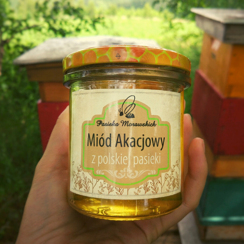 pasieka-morawskich-ekologiczny-miod-akacjowy-w-dloni-na-tle-uli