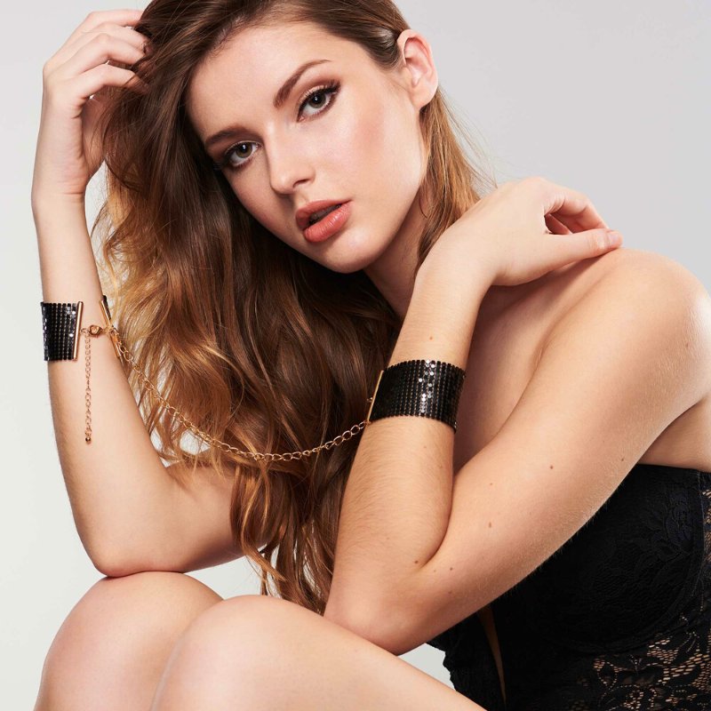 bijoux-indiscrets-desir-metallique-kajdanki-z-lancuszkow-czarne-na-dloniach-mlodej-kobiety