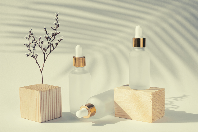 co-to-jest-hydrolat-i-jak-go-stosowac-w-codziennej-pielegnacji-szklane-minimalistyczne-buteleczki-z-hydrolatem-suszone-kwiaty-drewniane-kostki-na-jasnoszarym-tle