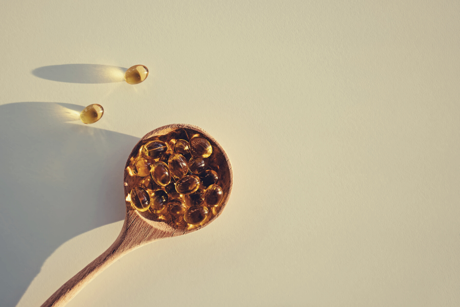 kapsulki-z-witamina-d-rozsypujace-sie-zdrewnianej-lyzki-na-jasnym-tle