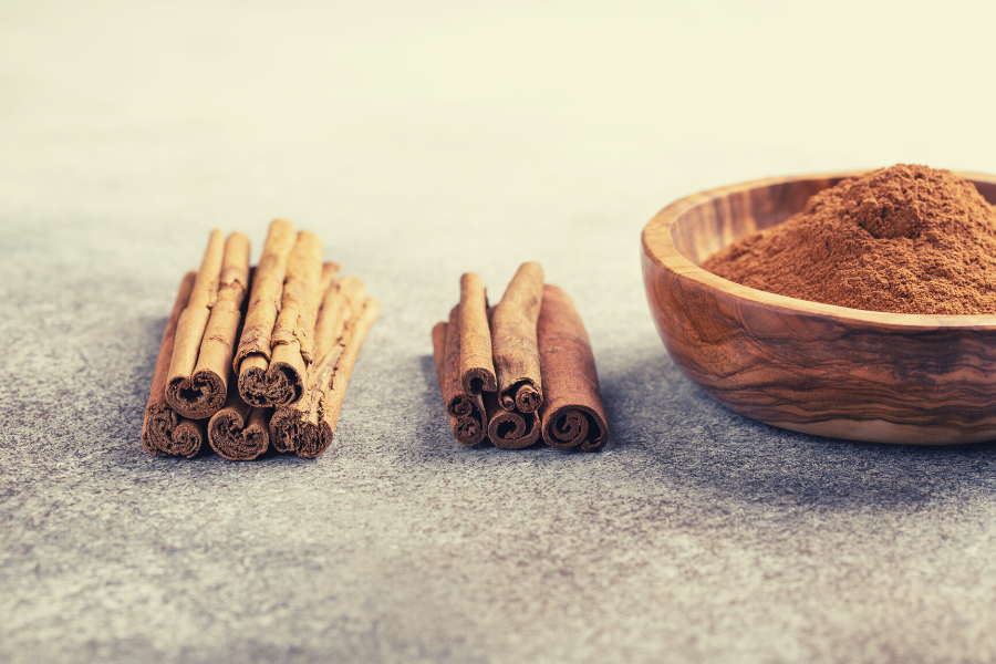 laski-cynamonu-cejlonskiego-i-cynamonu-kasja-drewniana-miseczka-ze-zmielonym-cynamonem-na-ciemnym-tle