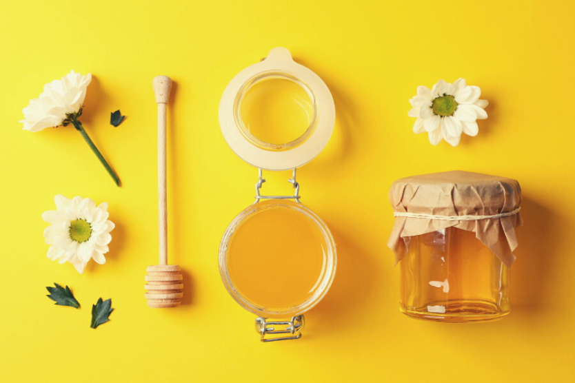 sloiczek-miodu-kwiaty-lyzka-do-miodu-na-zoltym-tle