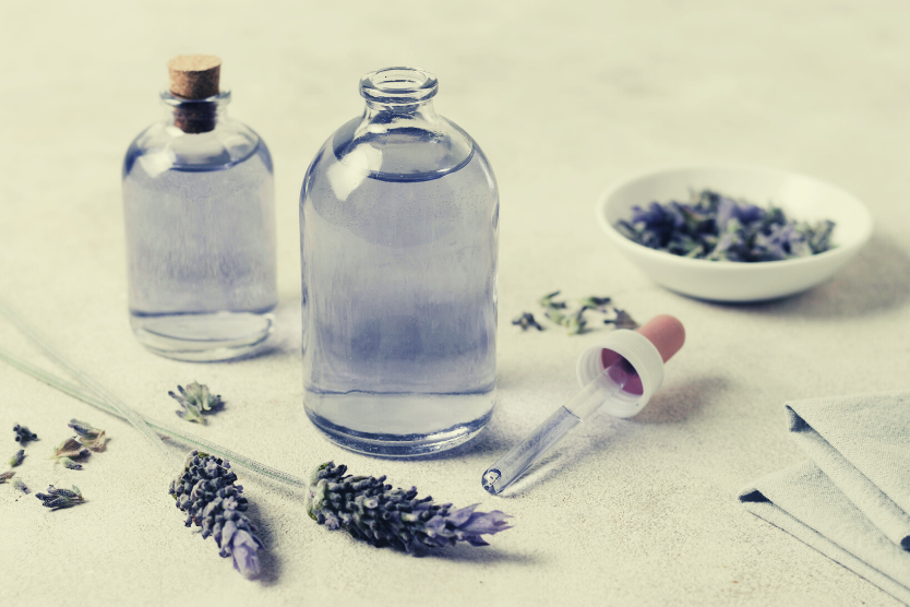 hydrolat-lawendowy-wlasciwosci-i-zastosowanie-kwiat-lawendy-szklane-butelki-z-woda-lawendowa-na-jasnym-tle