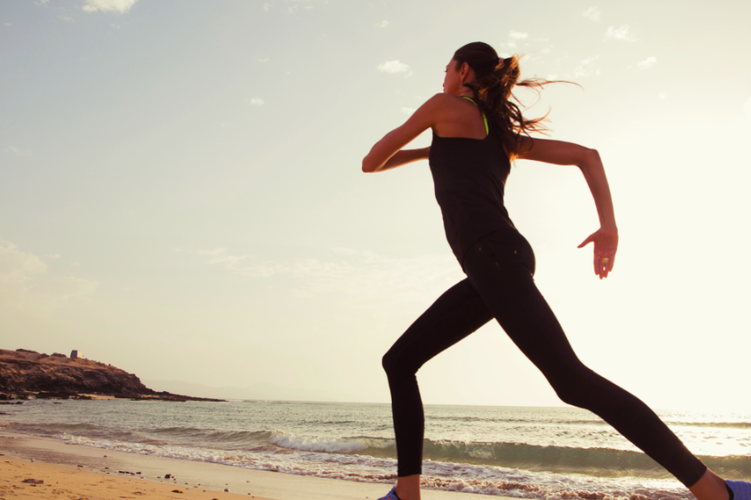 wysportowana-mloda-kobieta-biegnie-po-plazy-przy-zachodzie-slonca