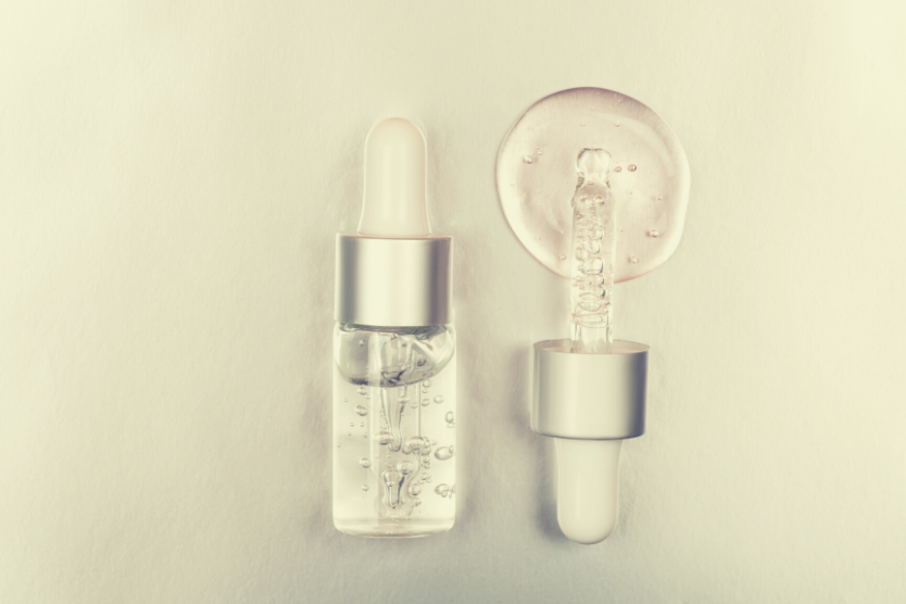 kwas-migdalowy-na-twarz-dzialanie-i-efekty-kosmetyczne-serum-w-szklanej-butelce-z-pipetka-na-jasnoszarym-tle