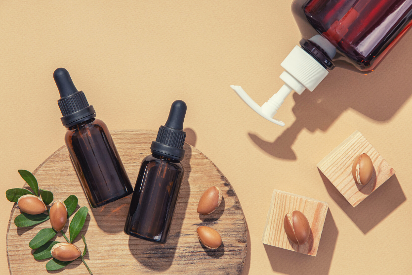 maseczki-domowej-roboty-z-olejkiem-arganowym-owoce-arganu-szklane-buteleczki-z-pipeta-na-drewnianej-podkladce-jasnobrozowe-tlo
