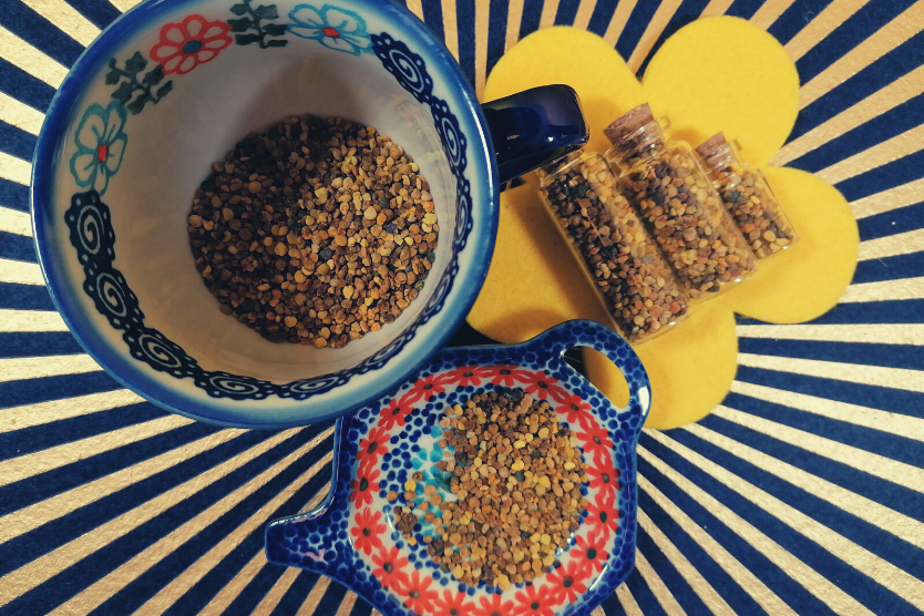 pylek-pszczeli-w-kolorowej-filizance-w-szklanych-butelkach-na-kolorowej-ceramicznej-figurce-w-ksztalcie-imbryczka-na-niebiesko-zlotym-tle