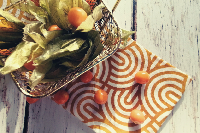 miechunka-zloty-owoc-ktory-warto-jesc-owoce-miechunki-na-bialo-pomaranczowym-materiale-miechunka-w-zlotym-koszyku