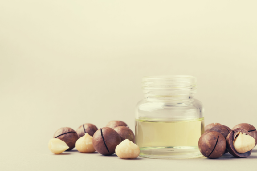 orzechy-makadamia-cale-i-czesciowo-obrane-maly-przezroczysty-sloik-z-olejem-z-otzrchow-makadamia-olej-makadamia-do-wlosow-korzysci-i-sposob-uzycia
