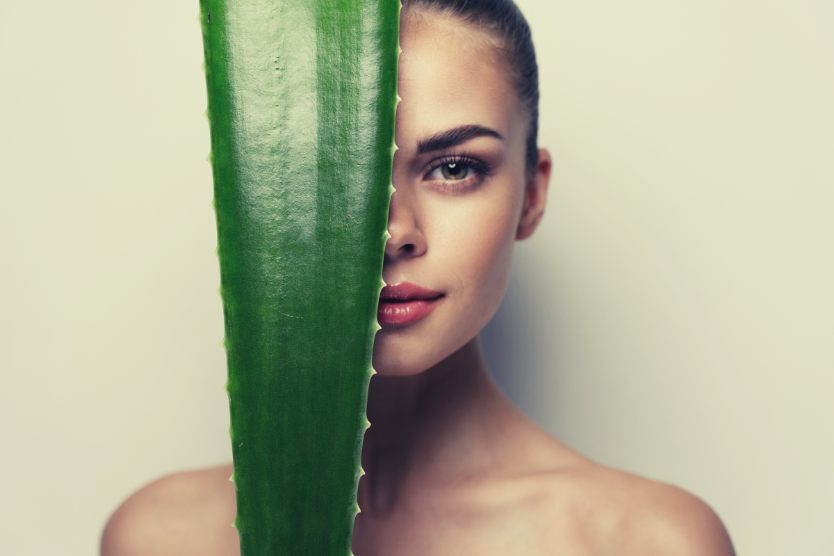 portret-mlodej-pieknej-brunetki-ze-zwiazanymi-wlosami-pol-twarzy-zasloniete-przez-duzy-lisc-aloesu-idealna-cera-i-cialo-odsloniete-ramiona