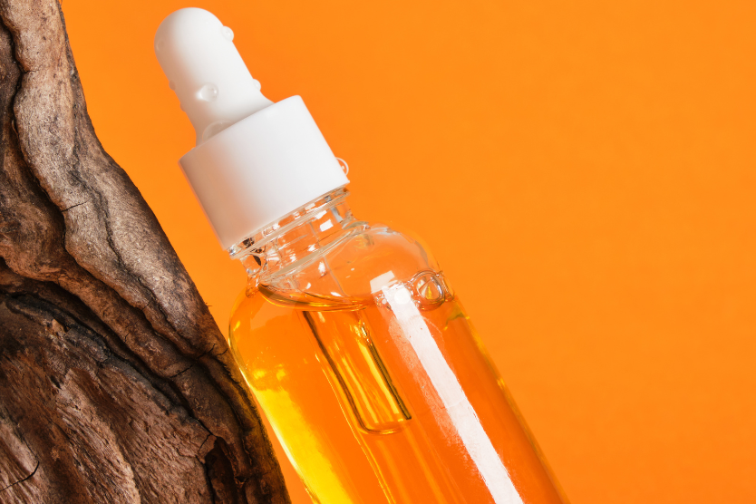 zloty-eliksir-mlodosci-odkryj-sekrety-oleju-z-nasion-marchwi-szklana-butelka-z-pipeta-z-olejem-z-nasion-marchwi-na-pomaranczowym-tle