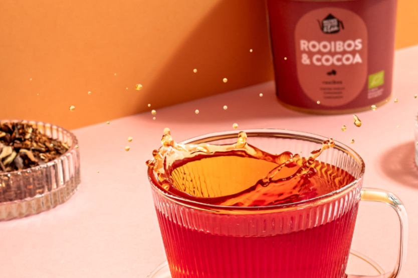 brown-house-tea-rooibos-cocoa-szklanka-z-zaparzonym-rooibosem-aromatyczna-herbata-w-drugim-planie-opakowanie-herbaty