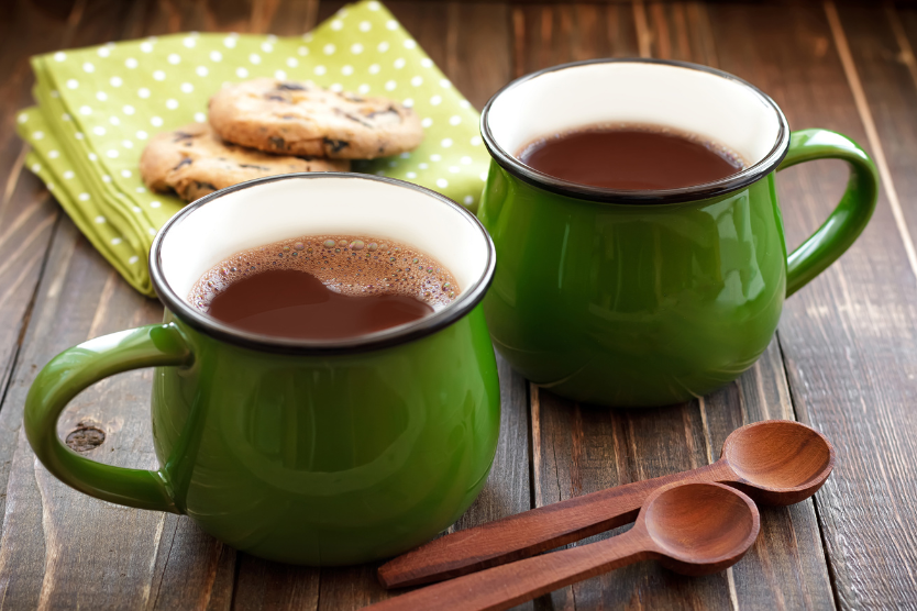 dwa-zielone-kubki-z-goracym-kakao-na-drewnianym-stole-w-tle-ciastka-i-serwetka-naturalny-napoj