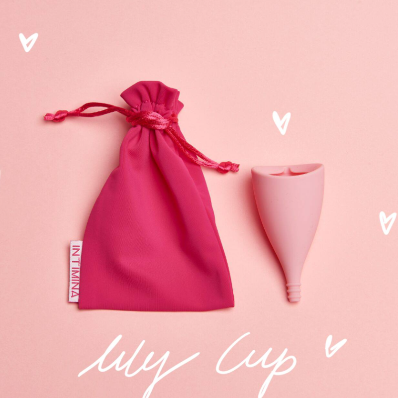 kubeczek-menstruacyjny-lily-cup-intimina-z-rozowym-woreczkiem-na-jasnorozowym-tle-z-elementami-graficznymi-serduszek-ekologiczny-i-stylowy-produkt-dla-kobiet