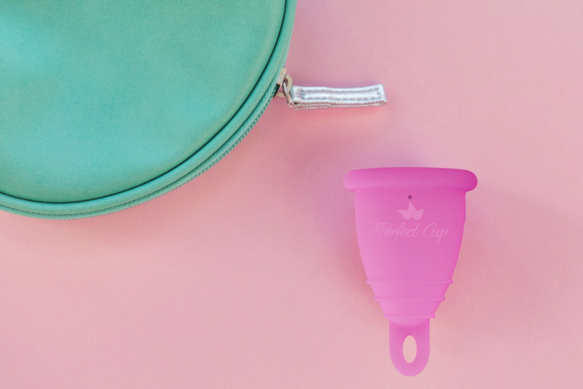 perfect-cup-rozowy-kubeczek-menstruacyjny-obok-turkusowej-kosmetyczki-na-pastelowym-rozowym-tle-ekologiczny-hipoalergiczny-produkt-intymny-wielorazowe