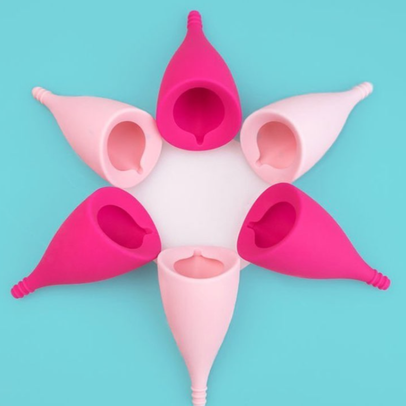 sześć-rozowych-kubeczkow-menstruacyjnych-lily-cup-intimina-ulozonych-w-ksztalt-kwiatu-na-niebieskim-tle-ekologiczne-wielorazowe-produkty-dla-komfortu-i-zdrowia-kobieT